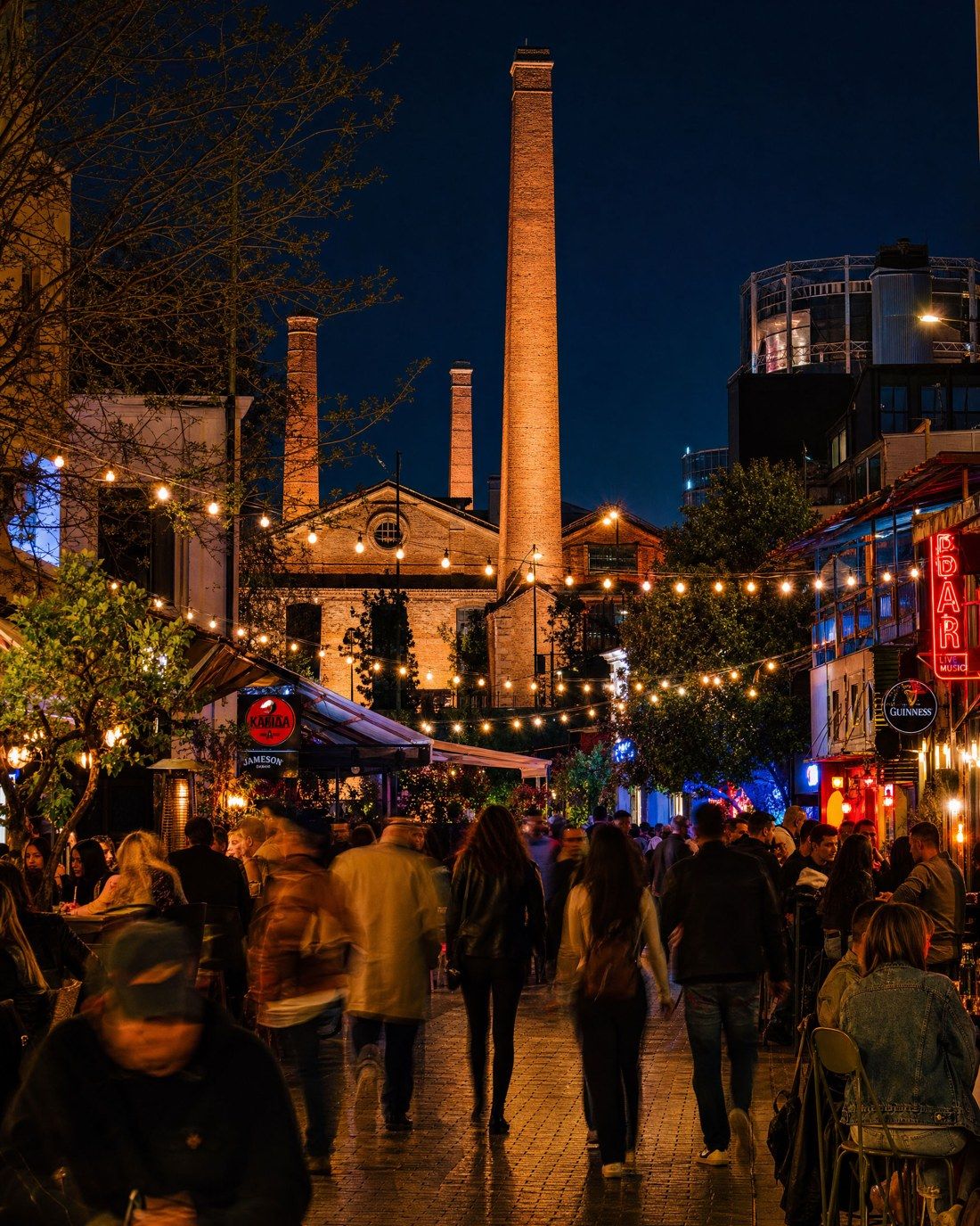 Gazi at night: bars, string lights, Technopolis chimney